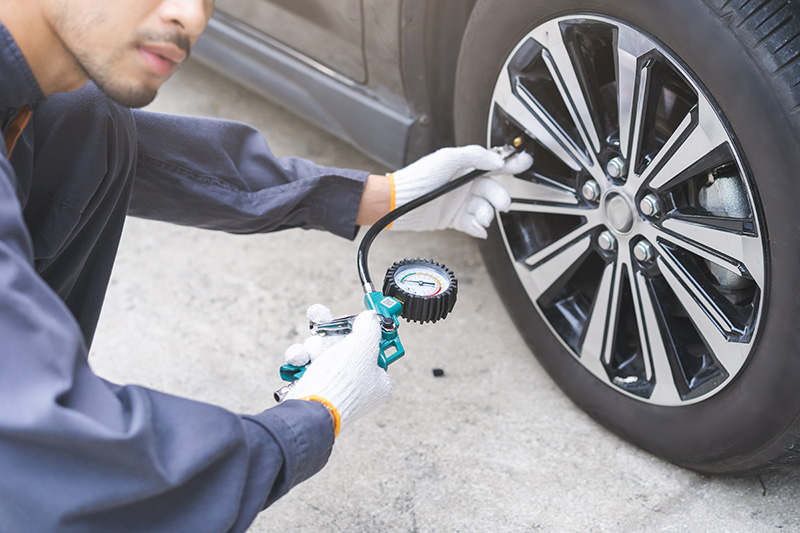 A mechanic checking tire pressure - Summer Car Service: Essential Tips for Drivers in Putnam, CT 